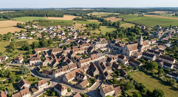 Photographie professionnelle de la ville d'Appoigny en Yonne prise depuis une perspective aérienne ou depuis un point élevé, montrant le centre-ville avec ses bâtiments caractéristiques, ses rues et le paysage rural environnant typique de l'Yonne. L'image doit transmettre un sentiment authentique de localisation dans une région française rurale, sans texte ni repères cartographiques, dans un style clair et professionnel adapté à un contexte B2C de menuiserie et fermetures.
